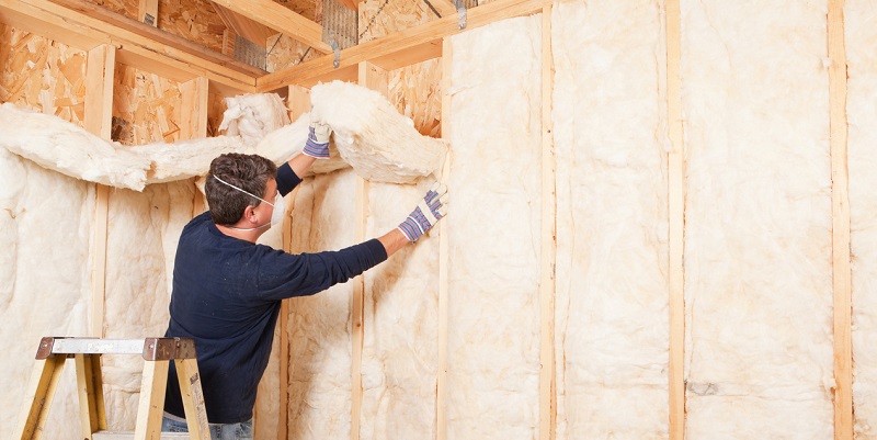 Construction Worker Insulating Wall with Fiberglass Batt